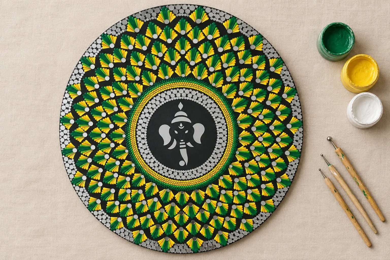 Gajanana in Green on linen beside dotting tools and pots of green, yellow, white paint